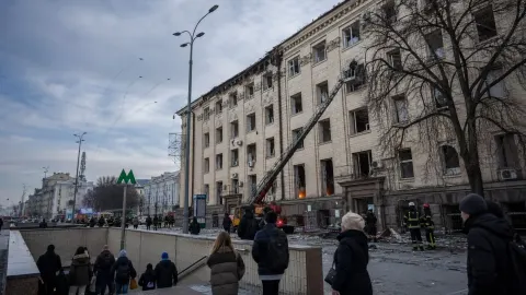 Emergency crews and residents outside a damaged city building after a drone alert in Kyiv.
