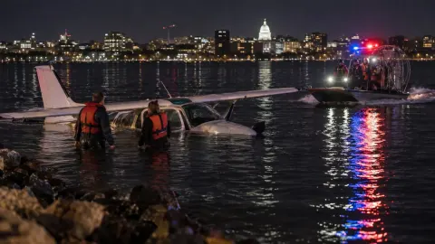 Editorial illustration of two anonymous survivors beside a partly submerged small plane as an airboat approaches on a city lake at night