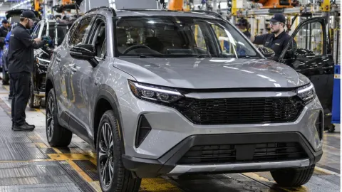 Editorial illustration of a modern hybrid SUV moving through a British car assembly line in Sunderland