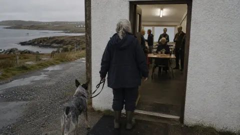 A woman and cattle dog at the entrance to a small community café on a Hebridean island