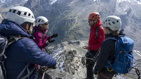 Two climbing parties in a tense discussion while clipped to a cable on a high Austrian ridge