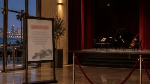 Editorial illustration of an empty theatre stage in Tel Aviv with a cancellation notice by the curtain
