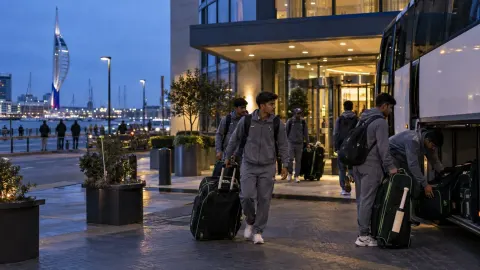 Editorial illustration of a cricket team coach parked outside a Portsmouth hotel in the evening