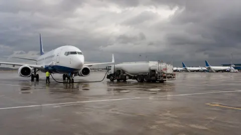 An unbranded budget passenger aircraft refuelling under dark winter clouds at a European airport