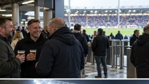 Editorial illustration of football supporters holding drinks in a modern English stadium concourse